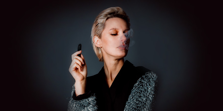 woman with blonde short hair vaping and holding a vape device